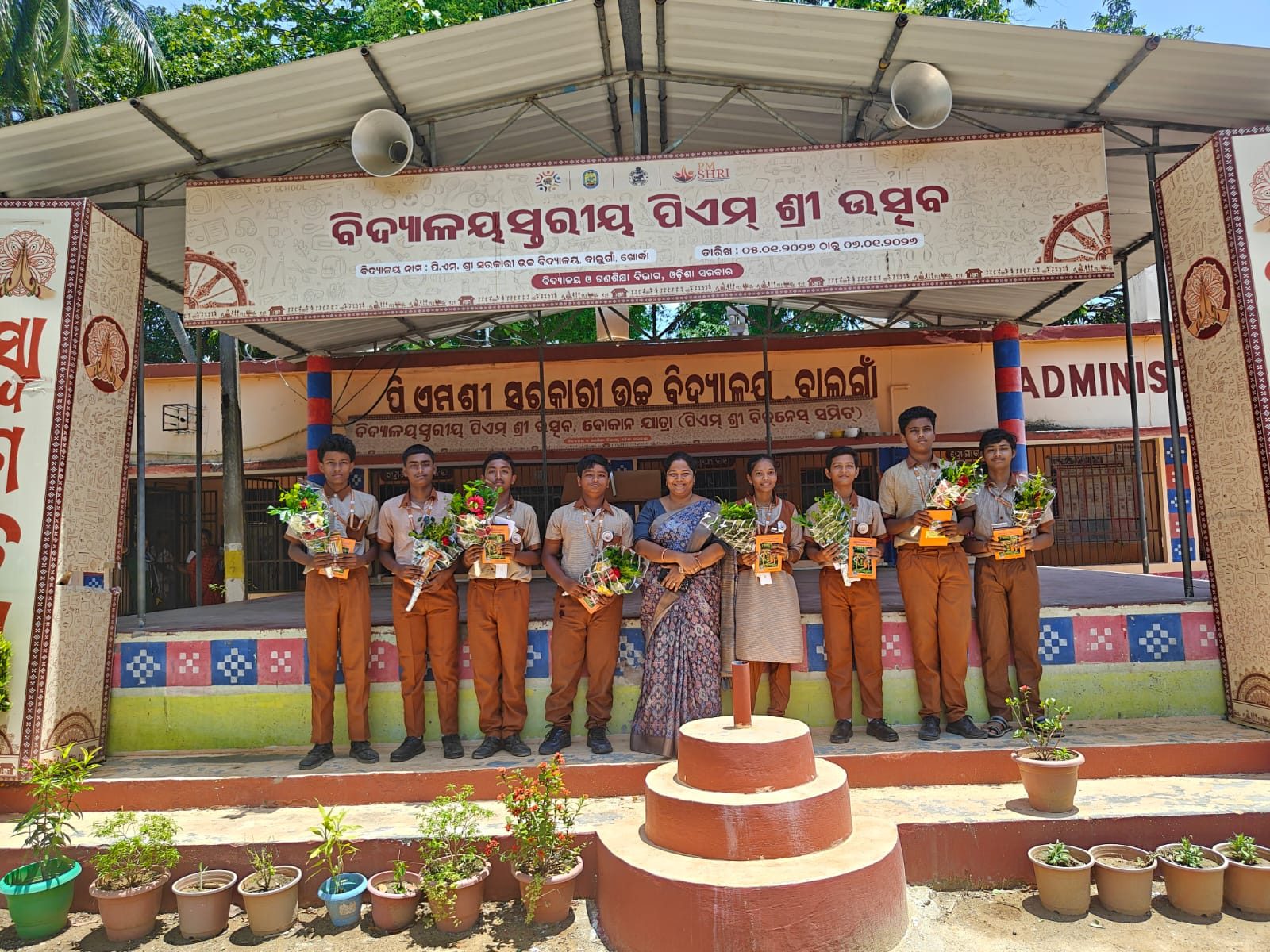 Students holding bouquets on the stage at the PM SHRI Utsav